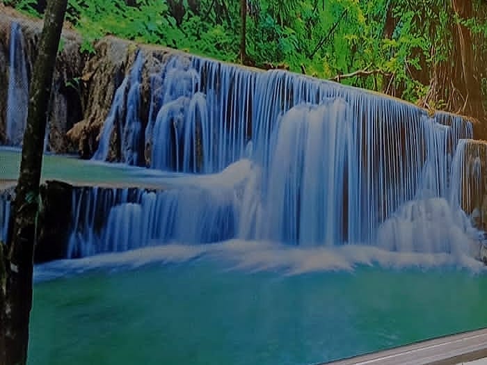 Vinilo decorativo con un paisaje de cascada aplicado sobre un ventanal